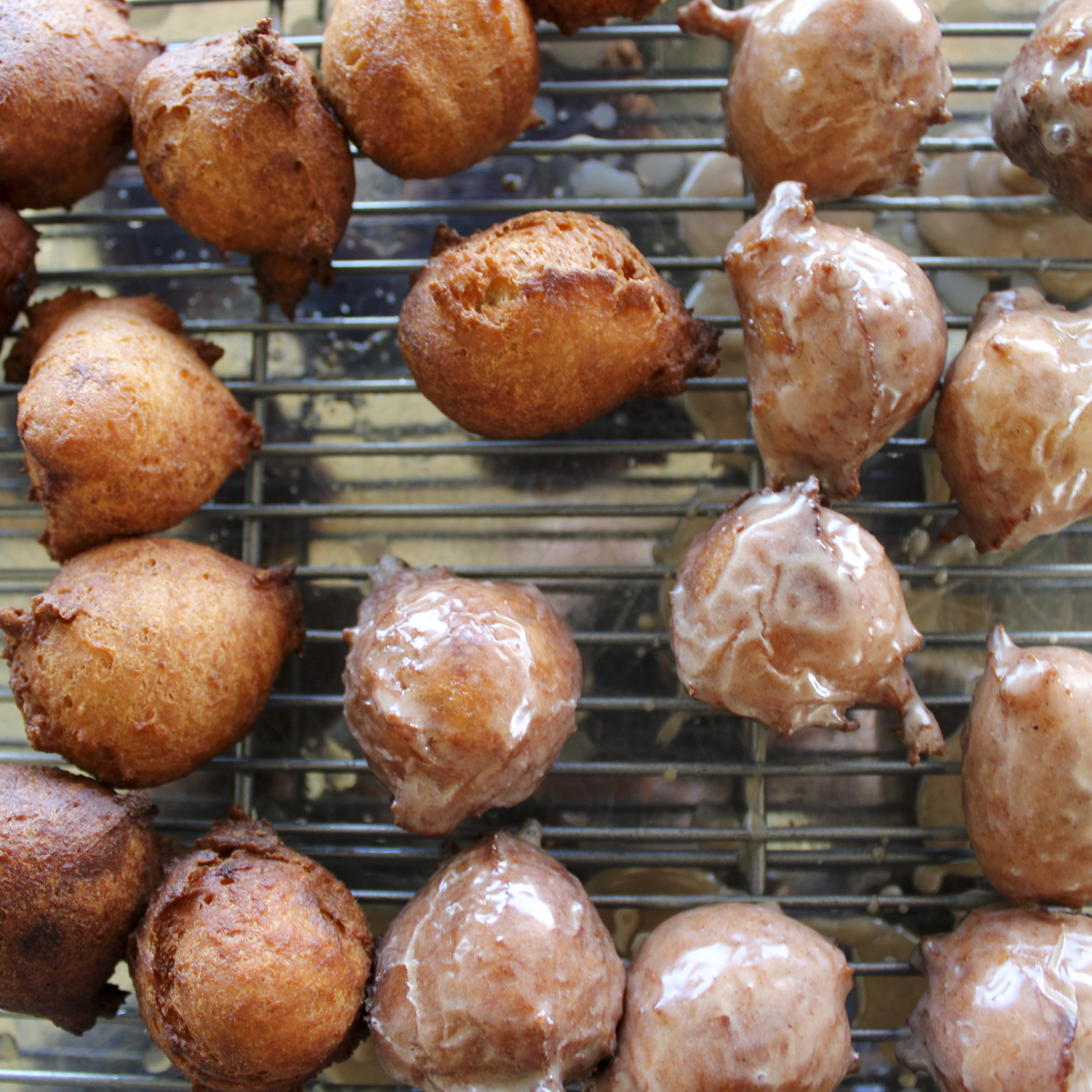 donut holes, glazed and plain, ona. wire rack sitting on a stainless steel cooking sheet
