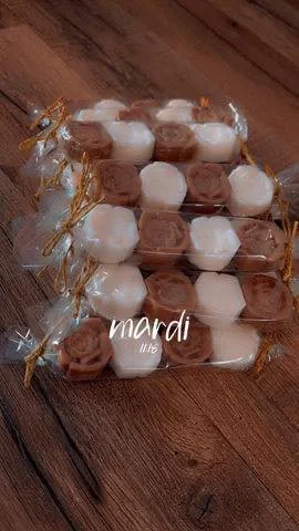 Paquets de bonbons ou chocolats emballés dans du plastique transparent avec des décorations dorées sur un plateau en bois.