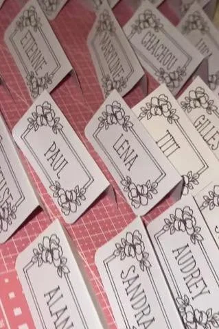 Cartes de nom avec des noms comme Paul, Lena, Audrey, Sandra, CLEGROT, Camille, Elise et d'autres, décorées de motifs floraux.