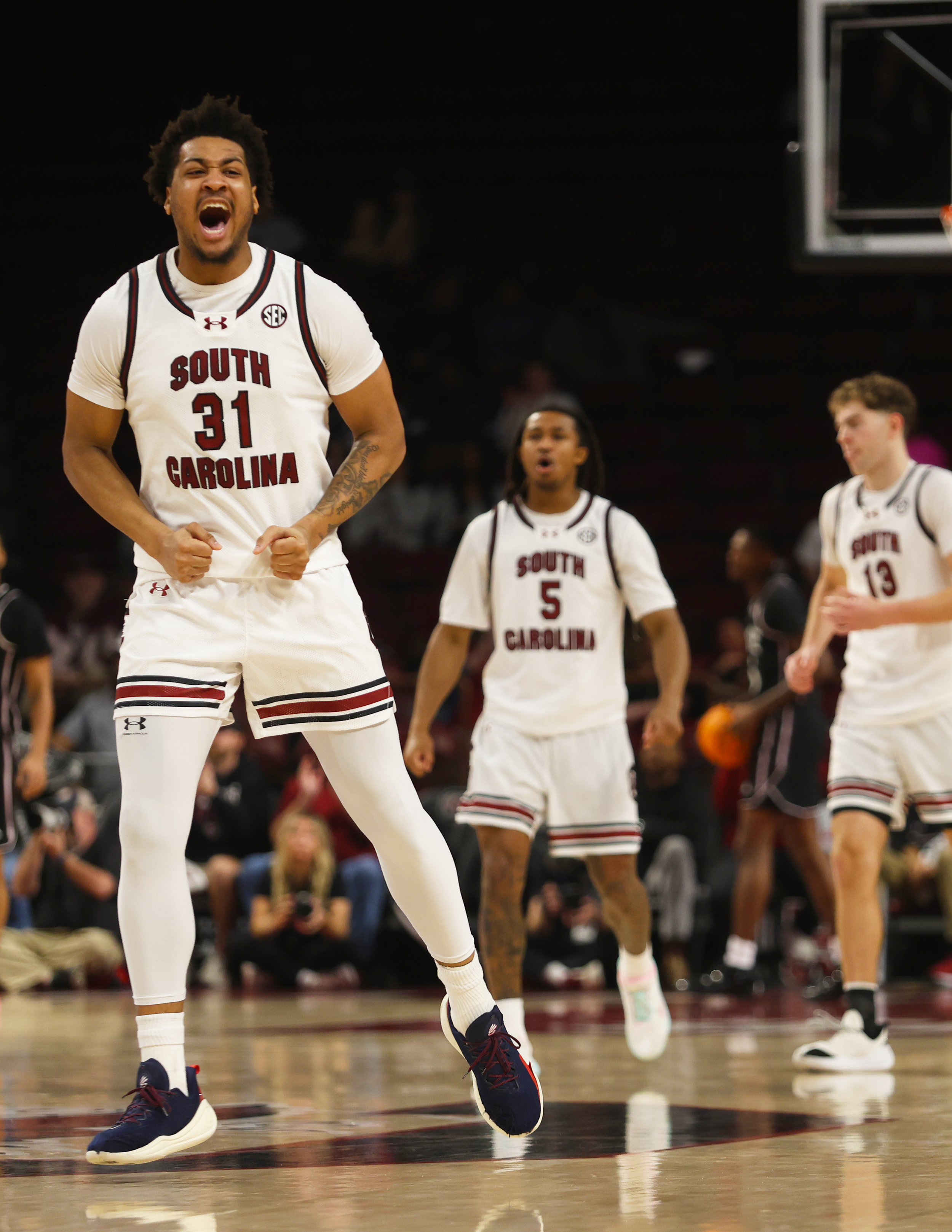 UofSC teammates Meechie Johnson (#5) and Grant Polk (#13) reacts to Junior Elijah Strong's (#31) successful three-point shot during South Carolina’s game against Mississippi State.