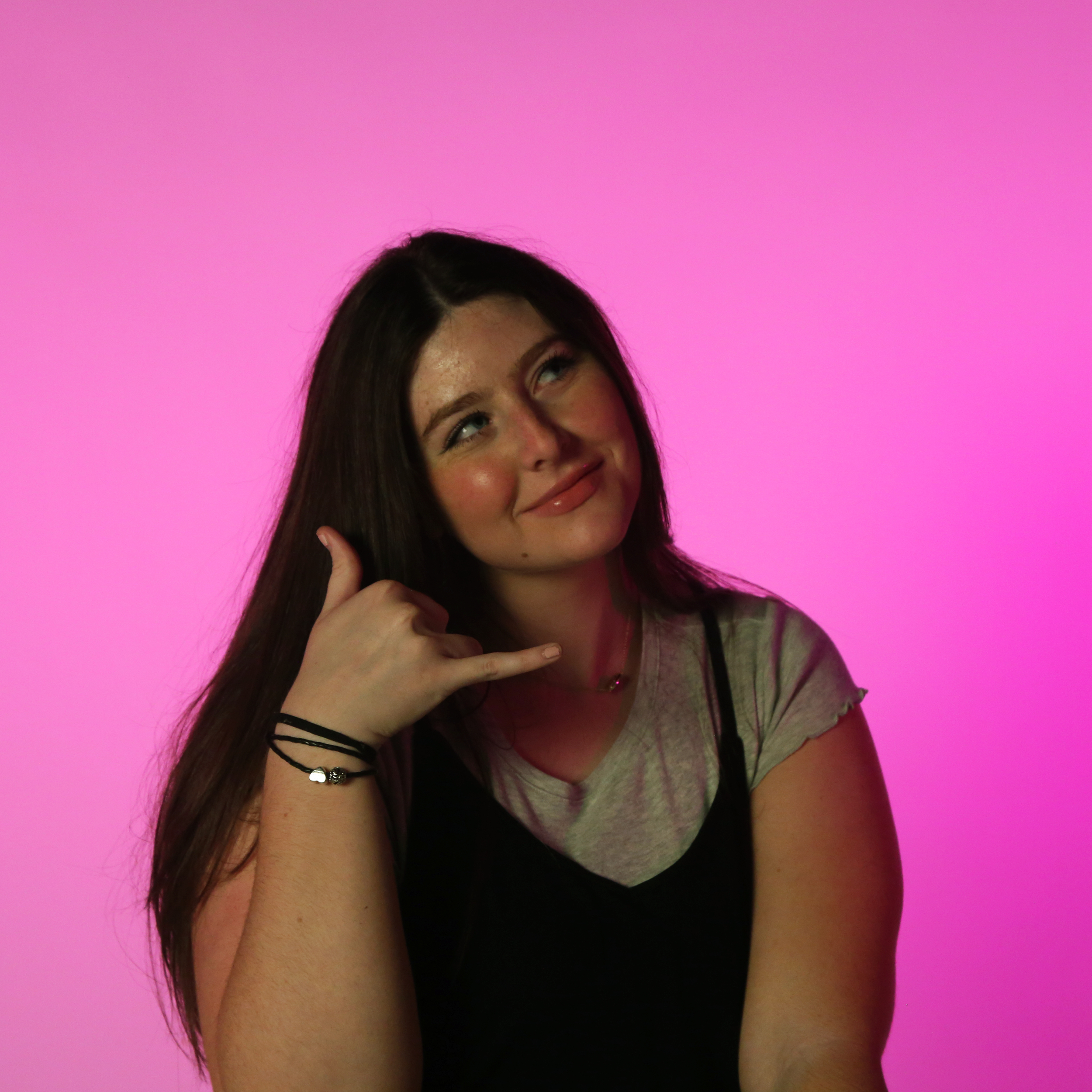 A studio portrait image from the session featuring model Ava Shreffler, designed to capture a playful and expressive side of her personality. Using bright pink studio lighting and a bold backdrop, this photograph emphasizes fun, creative posing and n