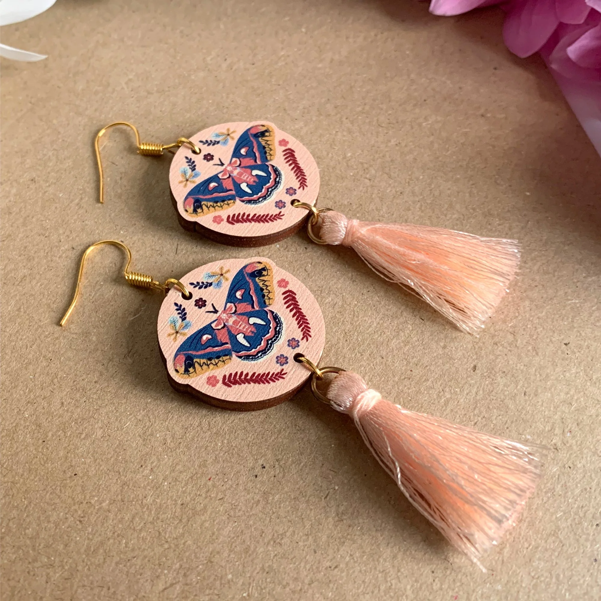 Bright colourful cut to shape earrings featuring a decorated moth with a pink tassel.