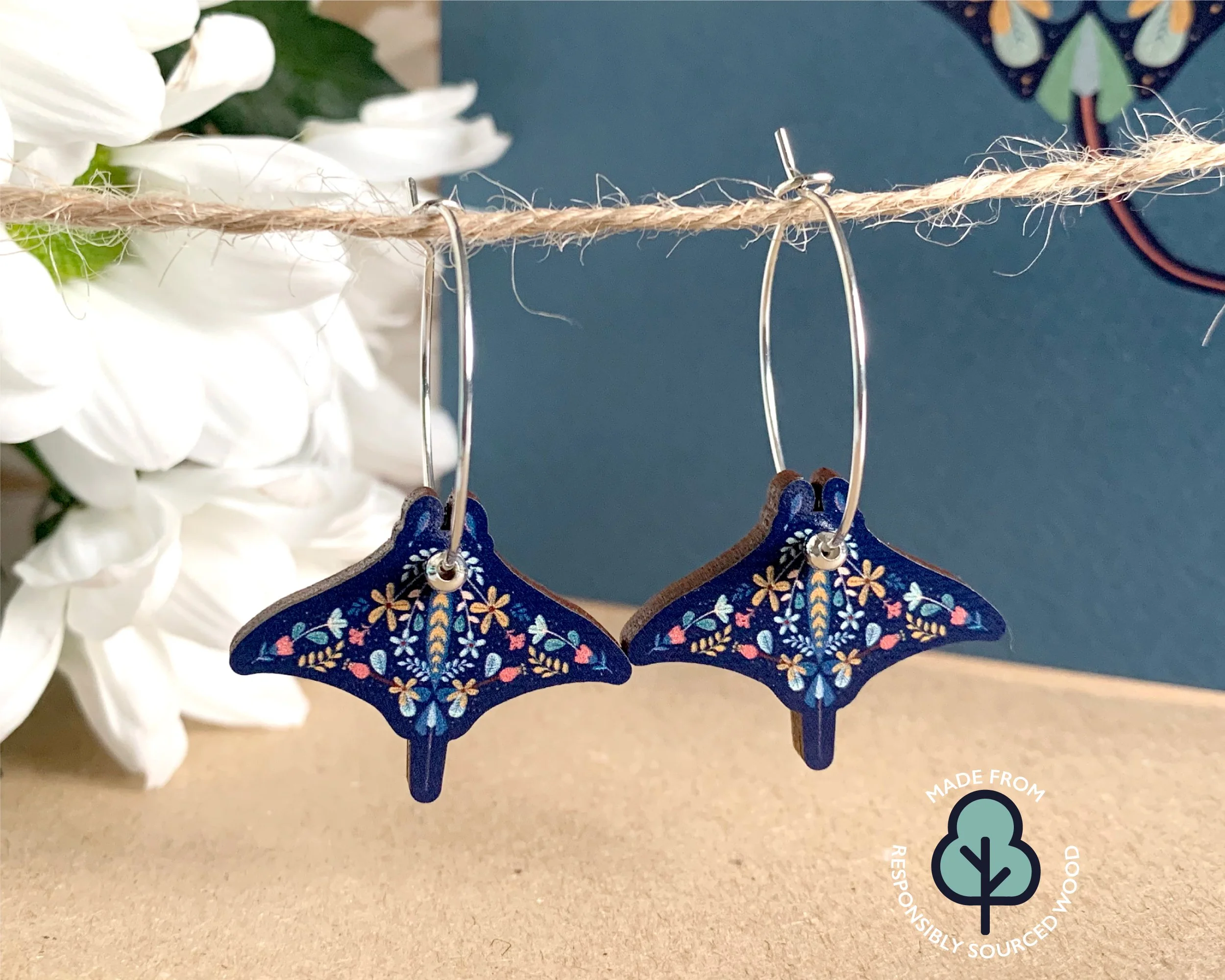 bright colourful flower decorated manta ray shaped wooden earrings, navy blue with colourful flowers on hoops with a silver bead.