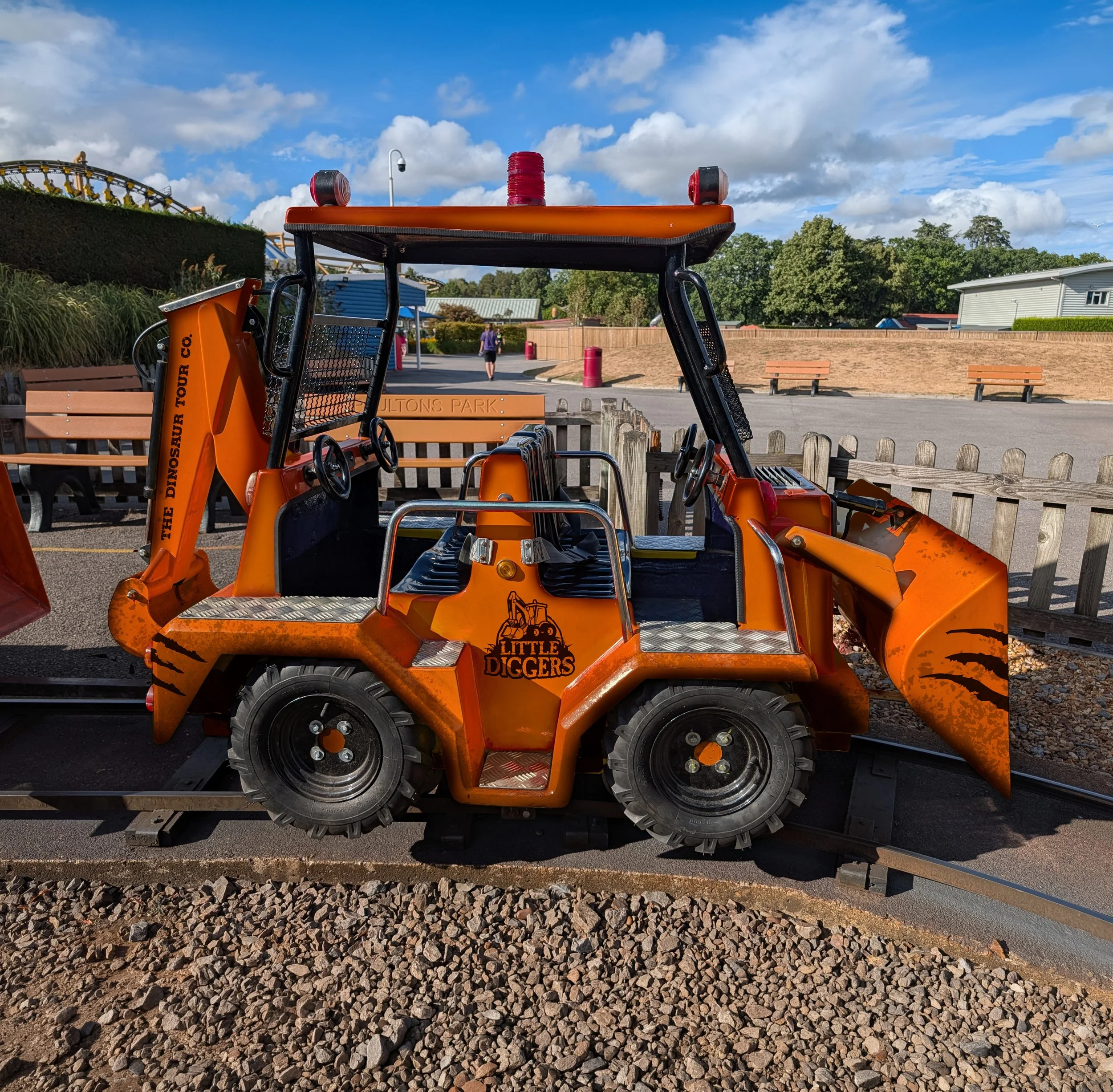 Orange theme park digger ride with Jurassic style branding and dinosaur decorations