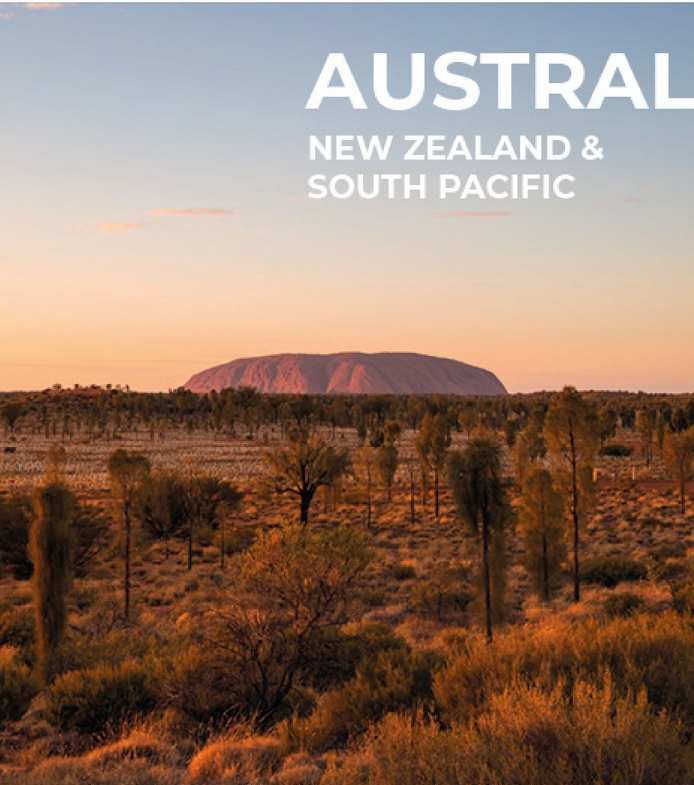 Sunset over Uluru in Australia with trees and desert landscape in foreground.