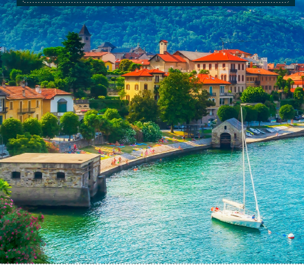 Coastal scene with boats on the water, buildings, and lush green mountains, with a clear blue sky.