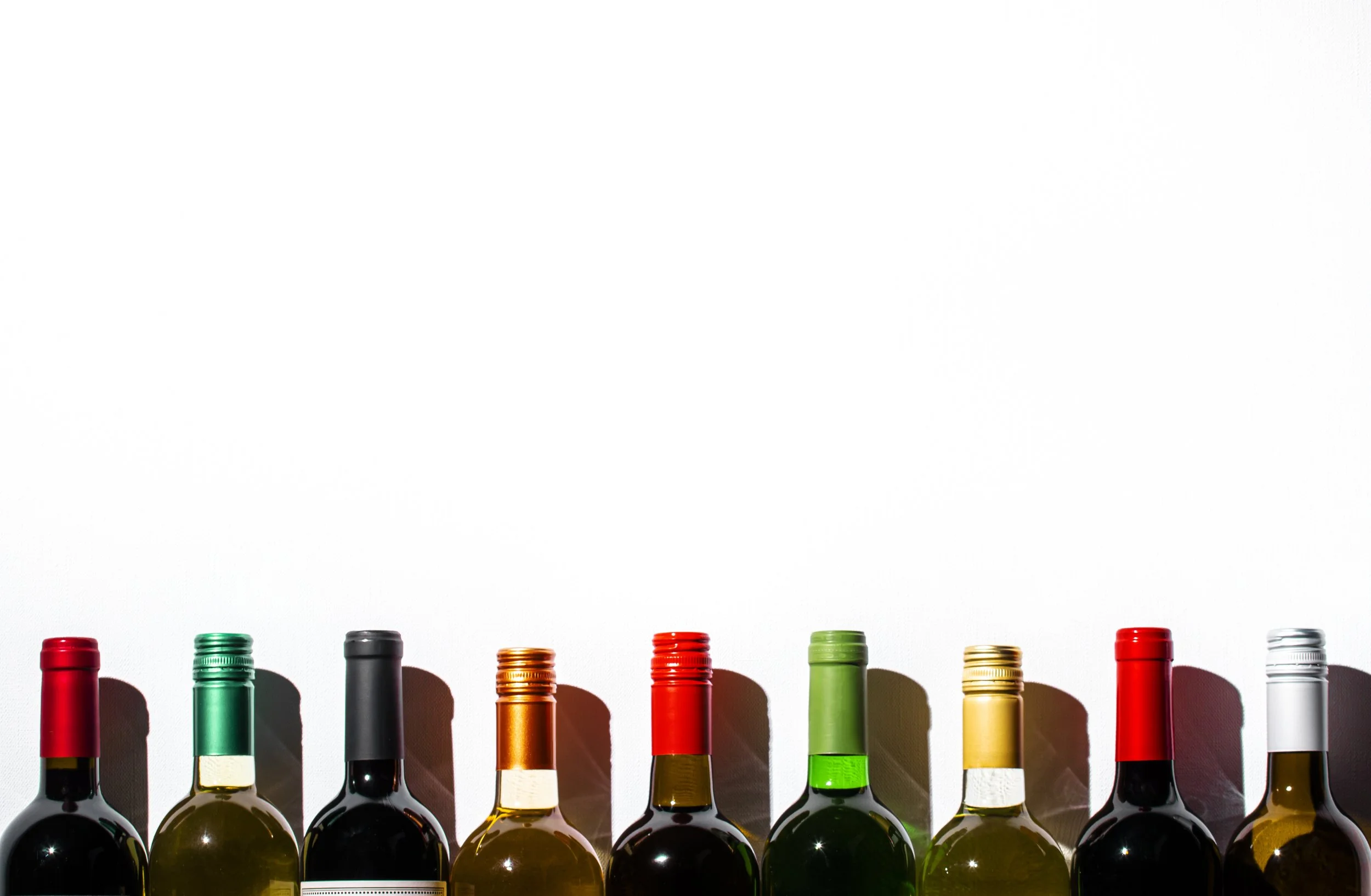 A handful of wine bottles lined up against a white background