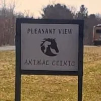 Sign that reads "Pleasant View Animal Clinic" with a dog logo, outdoors on a grassy area.