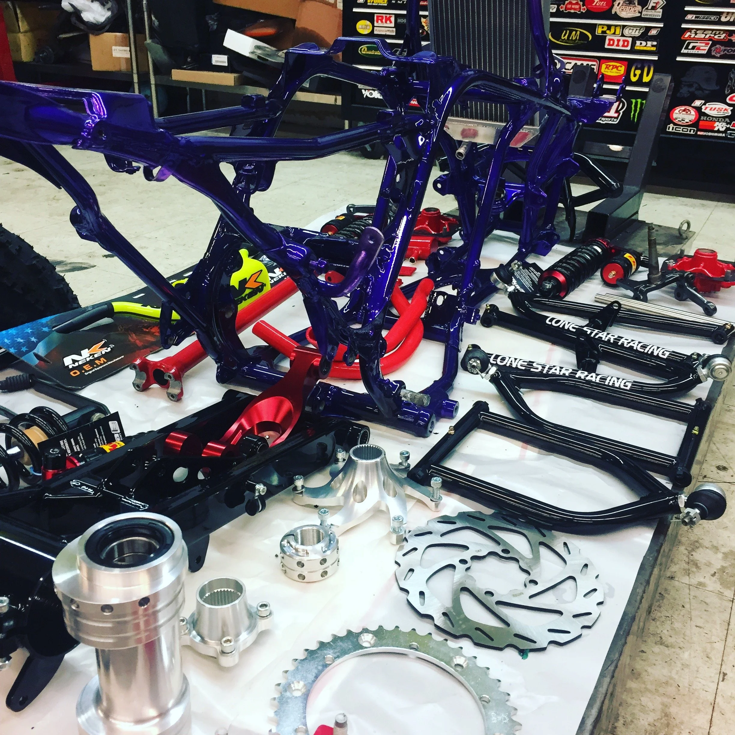 Disassembled motorcycle frame and parts laid out on a work table, including rotors, suspension components, and brackets.