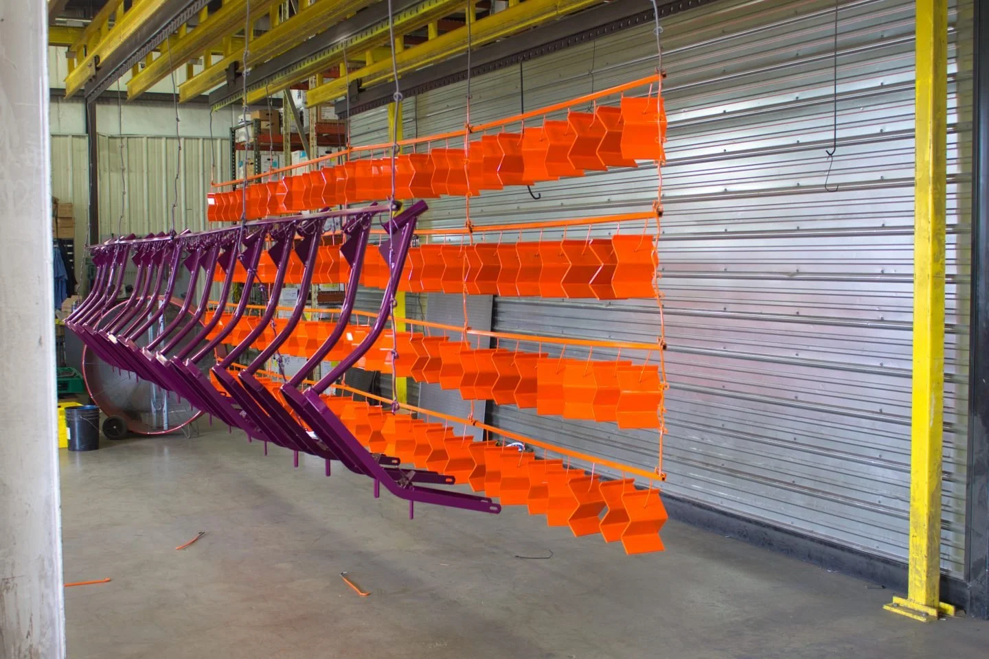 Orange and purple shelving units or carts hanging upside down inside a warehouse or industrial storage area.