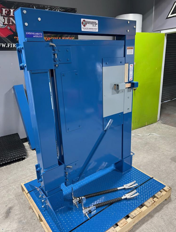 A blue industrial punching machine with long levers, set on a blue platform with hole patterns, placed on a wooden pallet in a workshop or store.