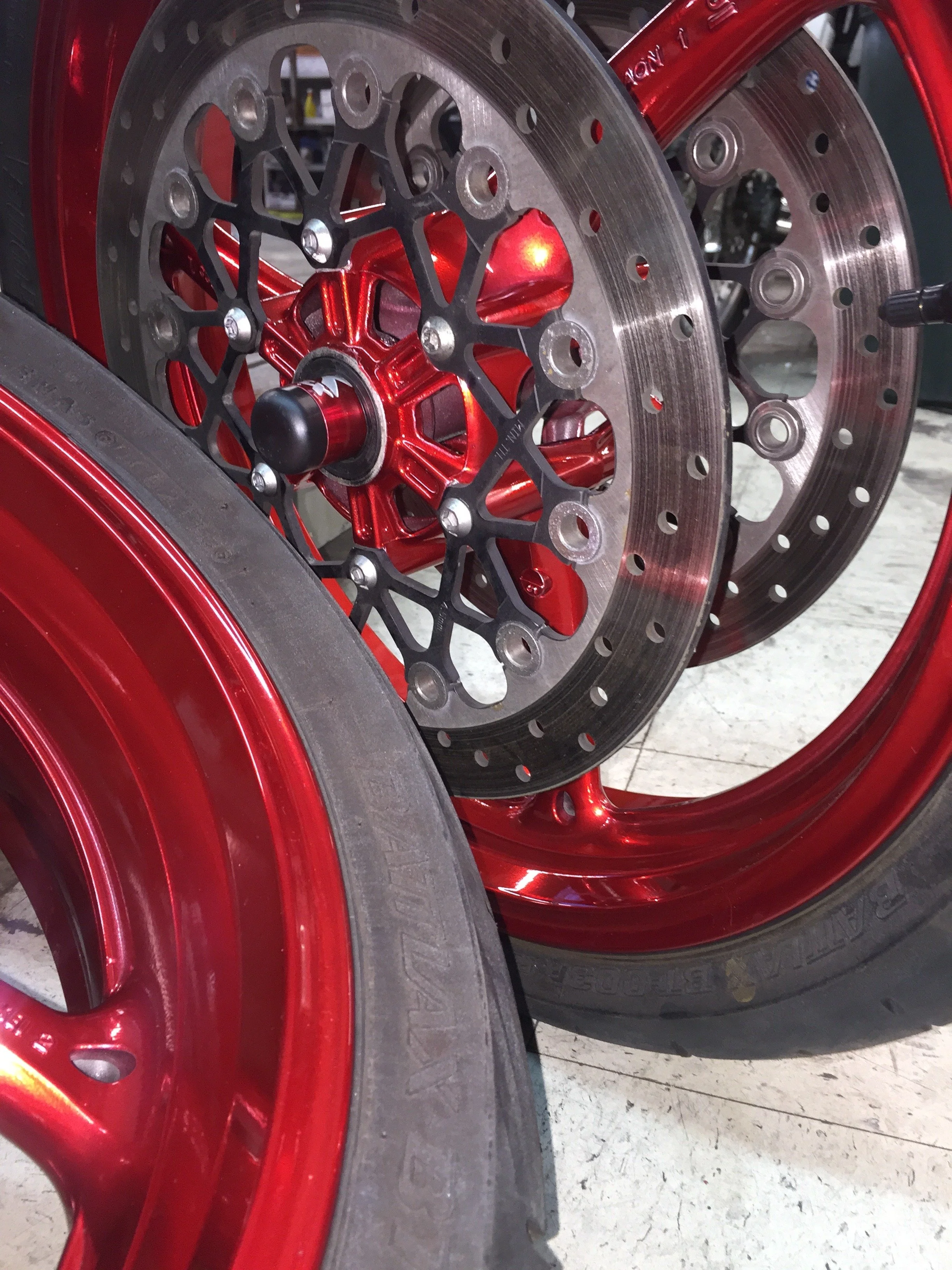 Close-up of motorcycle wheels with red rims, black axles, and silver brake discs