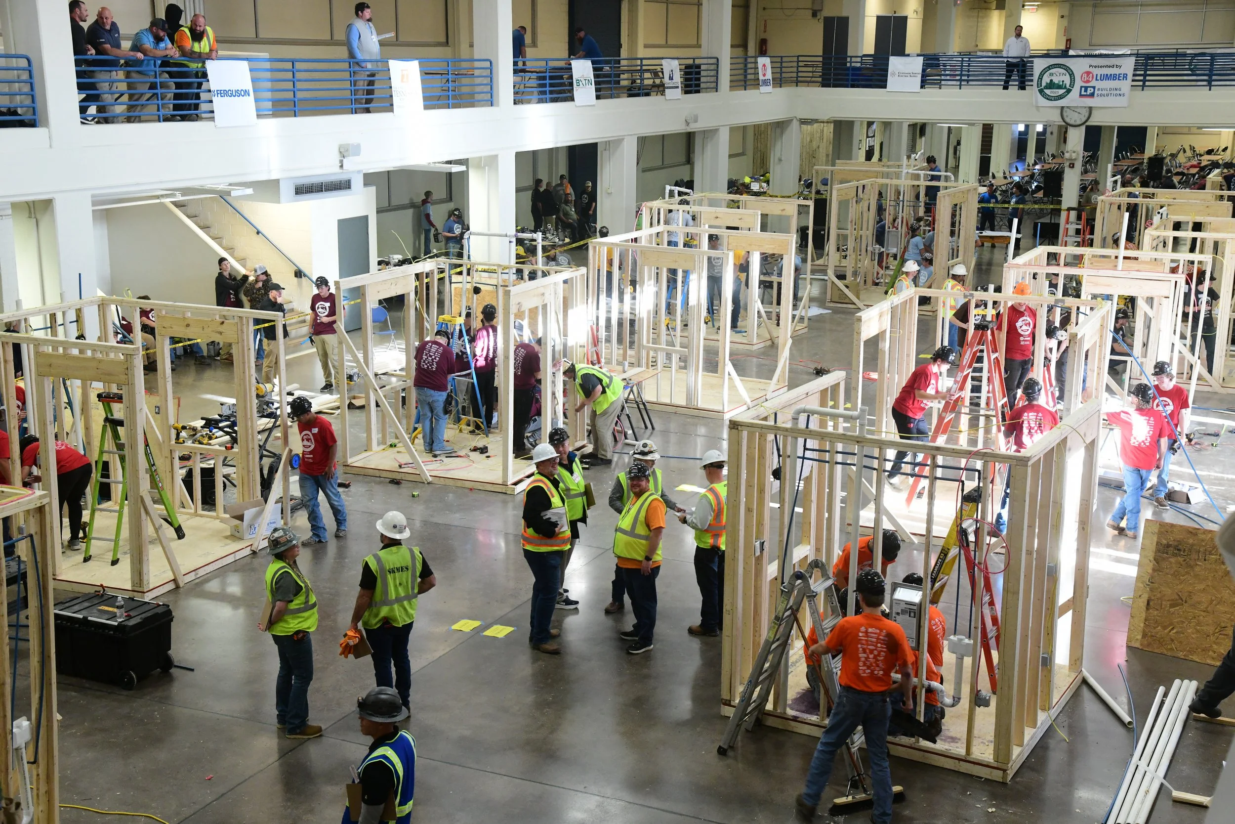 High School students building wooden frames inside a large industrial space as part of a construction competition.