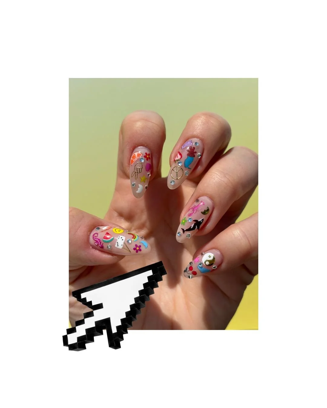 Close-up of a hand with colorful, decorated nail art featuring various small stickers and rhinestones, including flowers, smiley faces, animals, and abstract designs, with a pixelated arrow cursor overlayed in the bottom left.