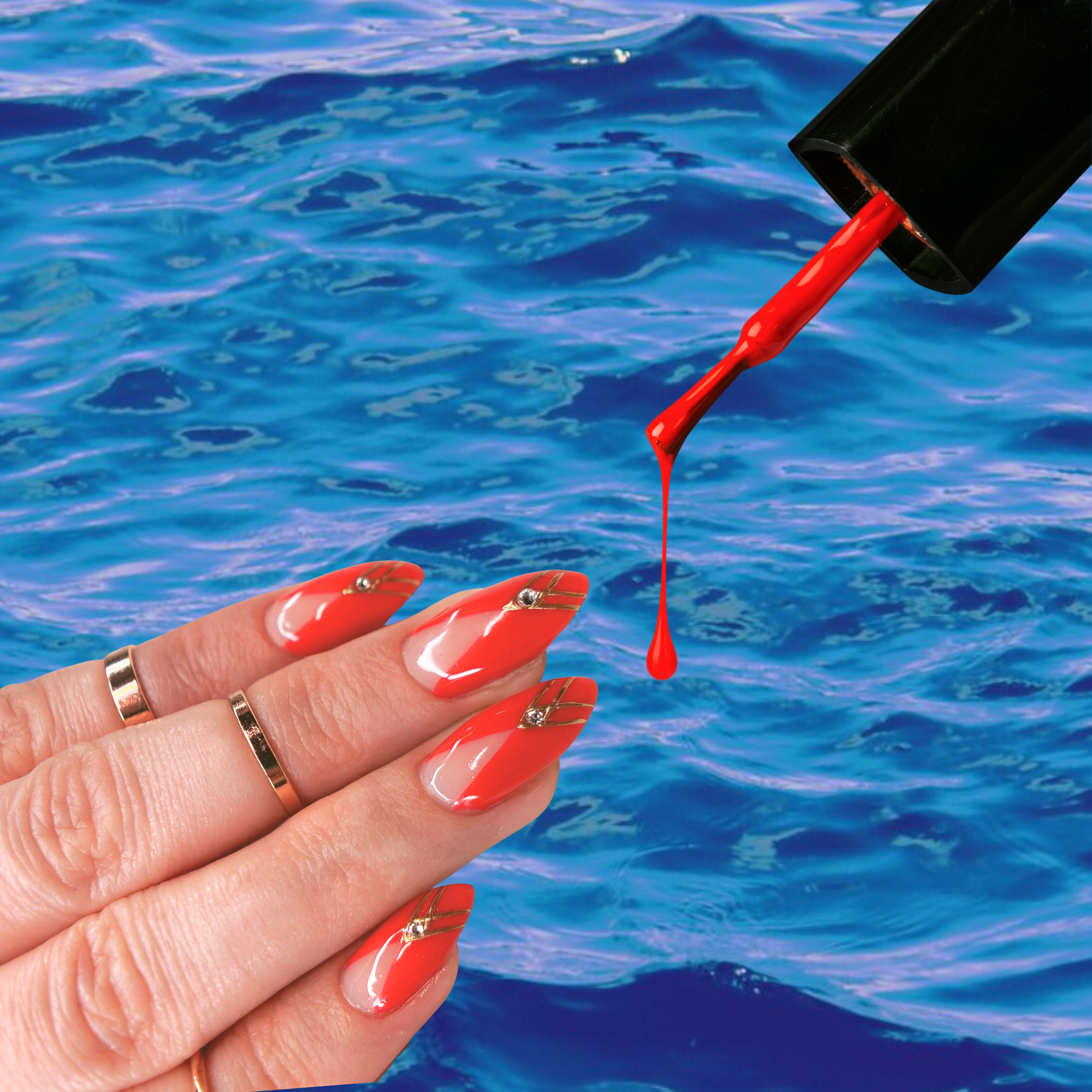 Close-up of a hand with decorated manicure holding a small vial dispensing red nail polish over water.