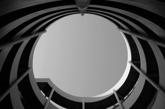View from the bottom of a spiral staircase looking up at the open sky