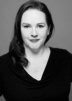 Black and white portrait of a woman with dark hair and a slight smile, wearing a dark top.