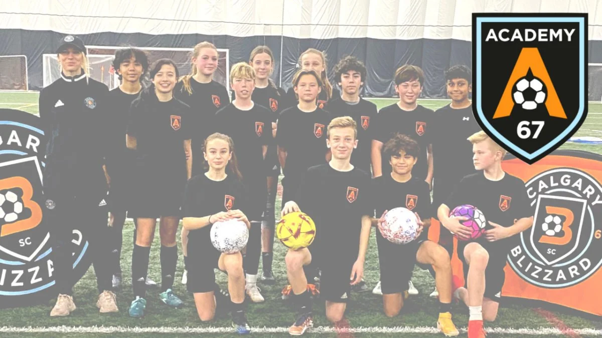 A youth soccer team with players and coaches posing on an indoor field, with team logos and two players holding soccer balls.