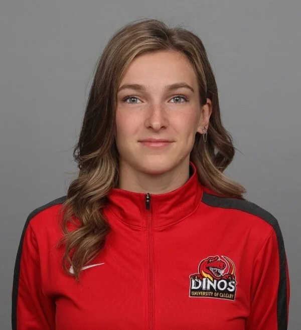 Young woman in a red sports jacket with university and team logos, facing forward with a neutral expression.