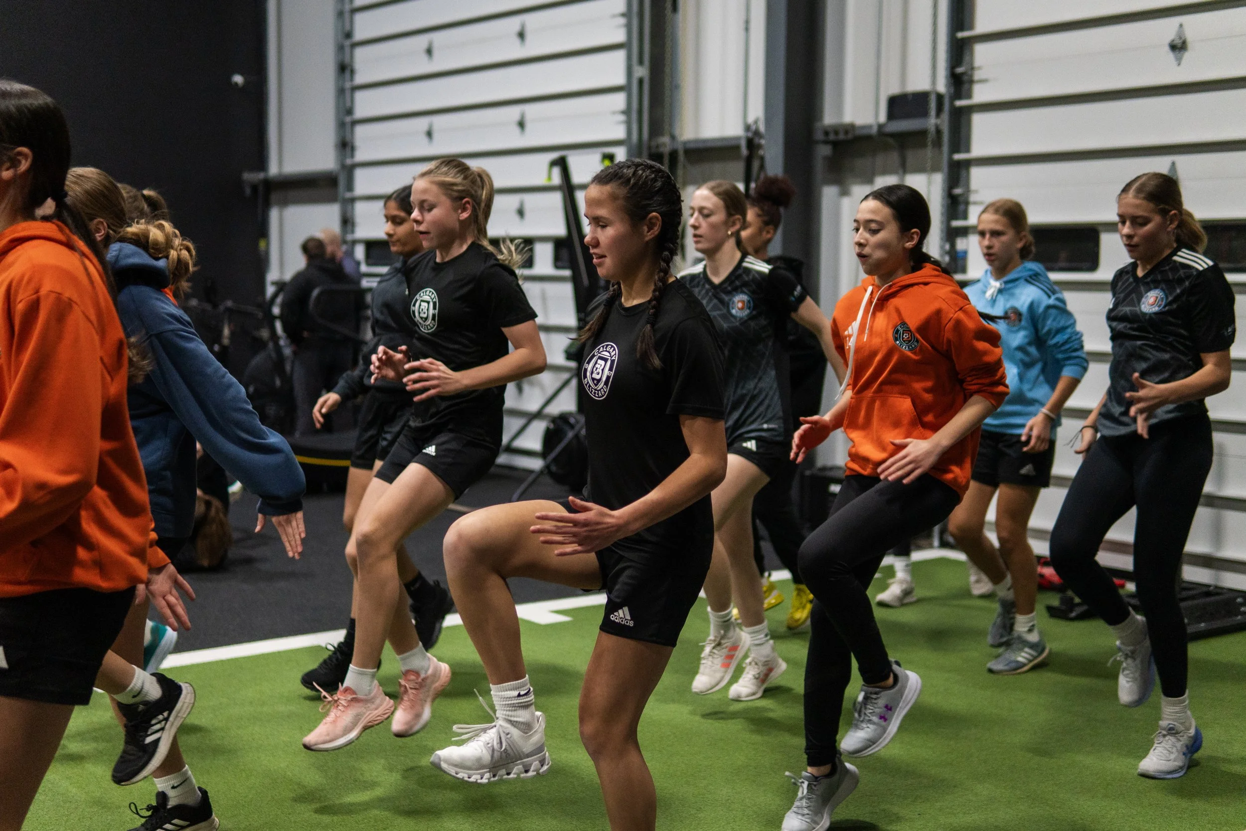 Group of women and girls doing indoor fitness or dance exercise together in a gym or training facility.