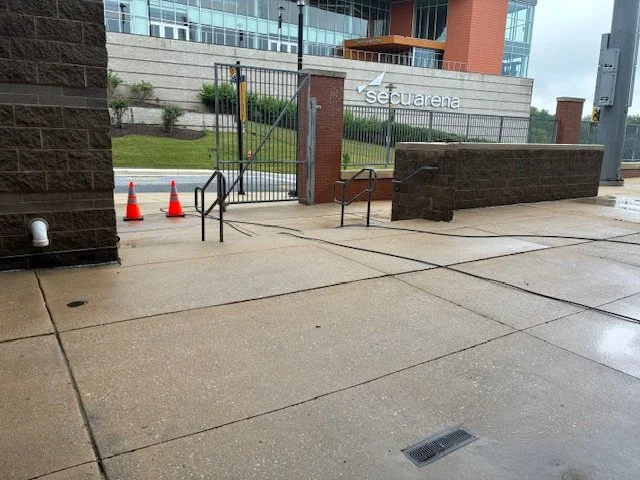 Wet sidewalk outside the SecuImage building with orange traffic cones and a gated entrance.