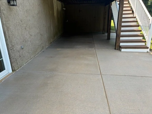 Empty concrete patio with stairs leading up to a deck or balcony.