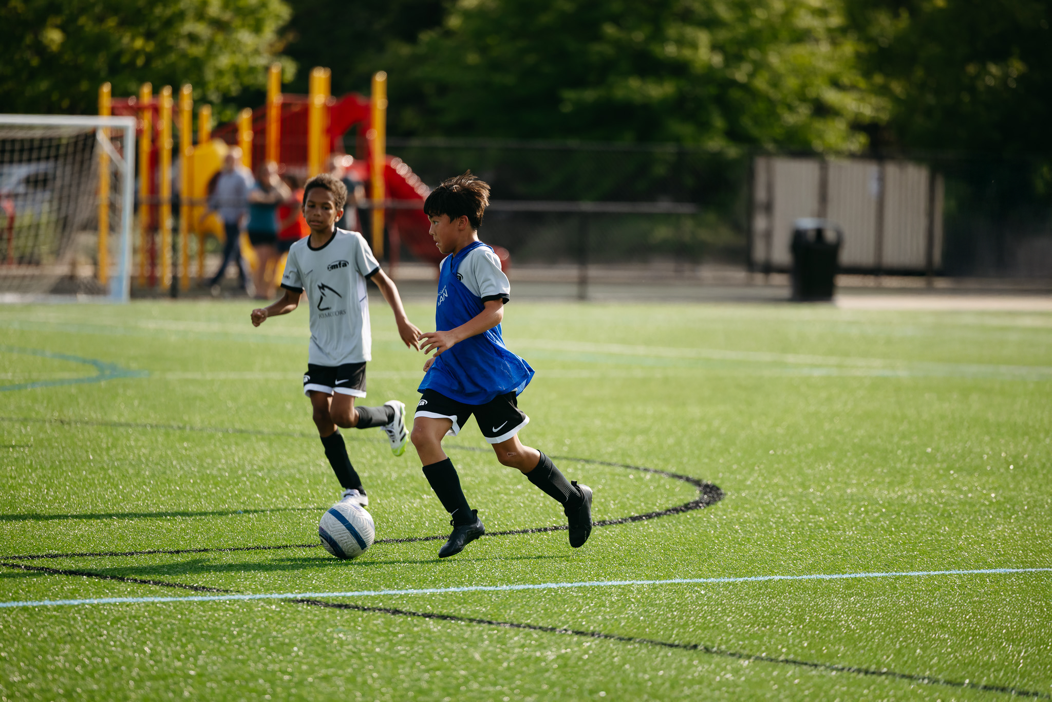Youth soccer players compete for the ball during a training game on an outdoor turf field in Grand Rapids, Michigan.