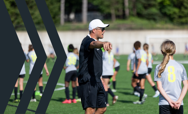 Soccer coach giving instructions to young players on a field during practice or game.