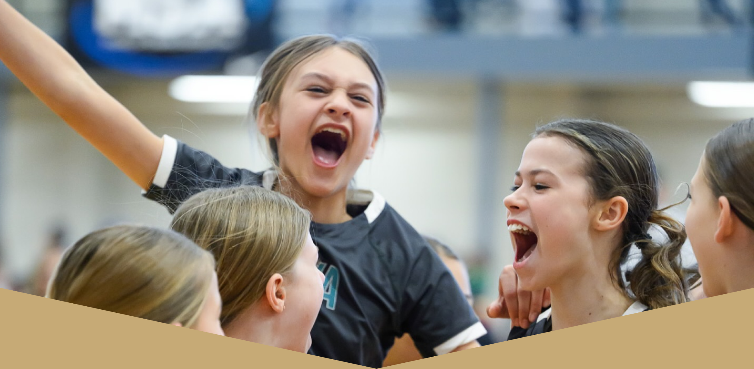 Group of young girls celebrating, smiling, and cheering indoors.