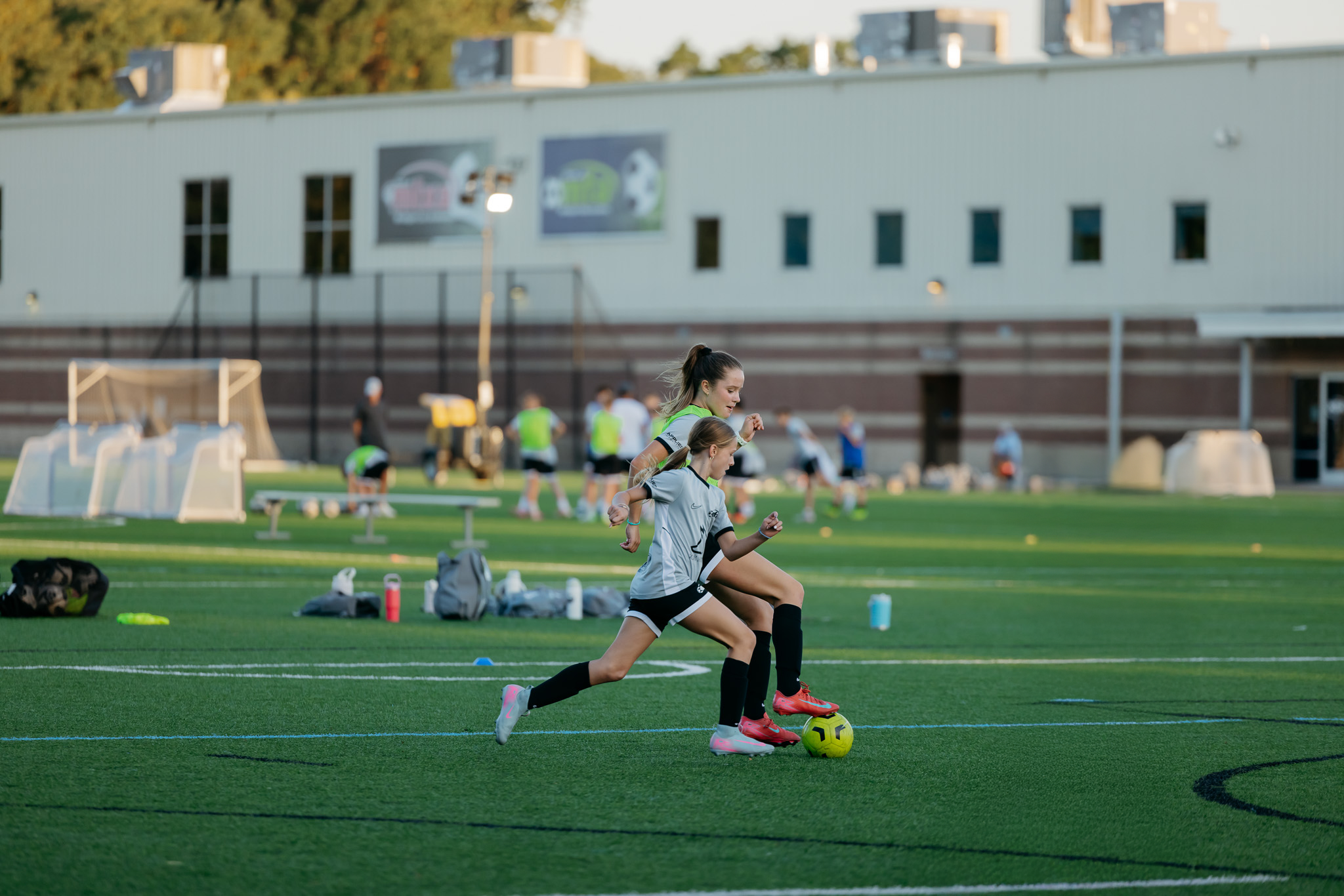 Girls youth soccer players compete for the ball during an outdoor training session on a turf field in Grand Rapids, Michigan.