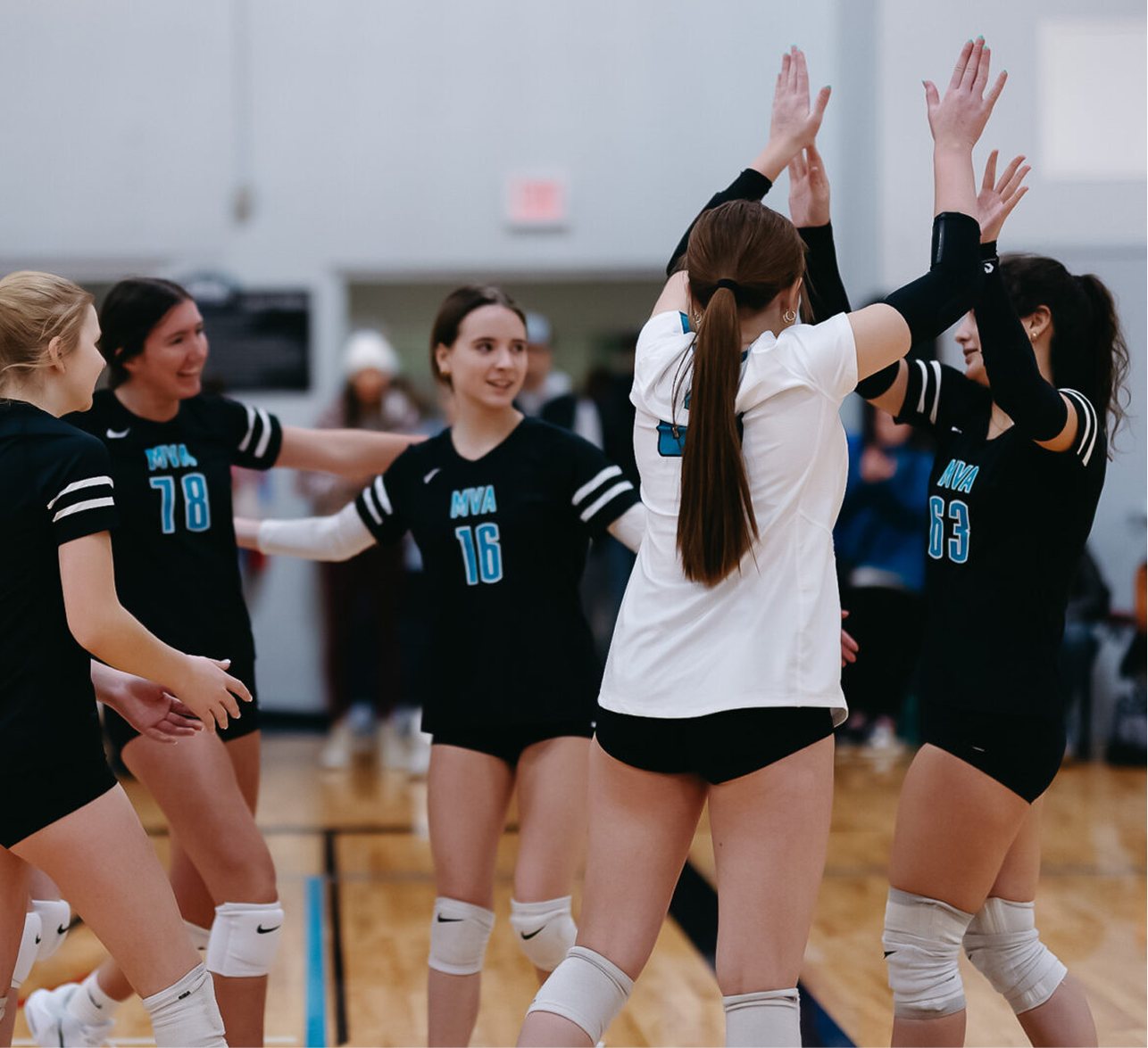 A volleyball team celebrating on indoor court