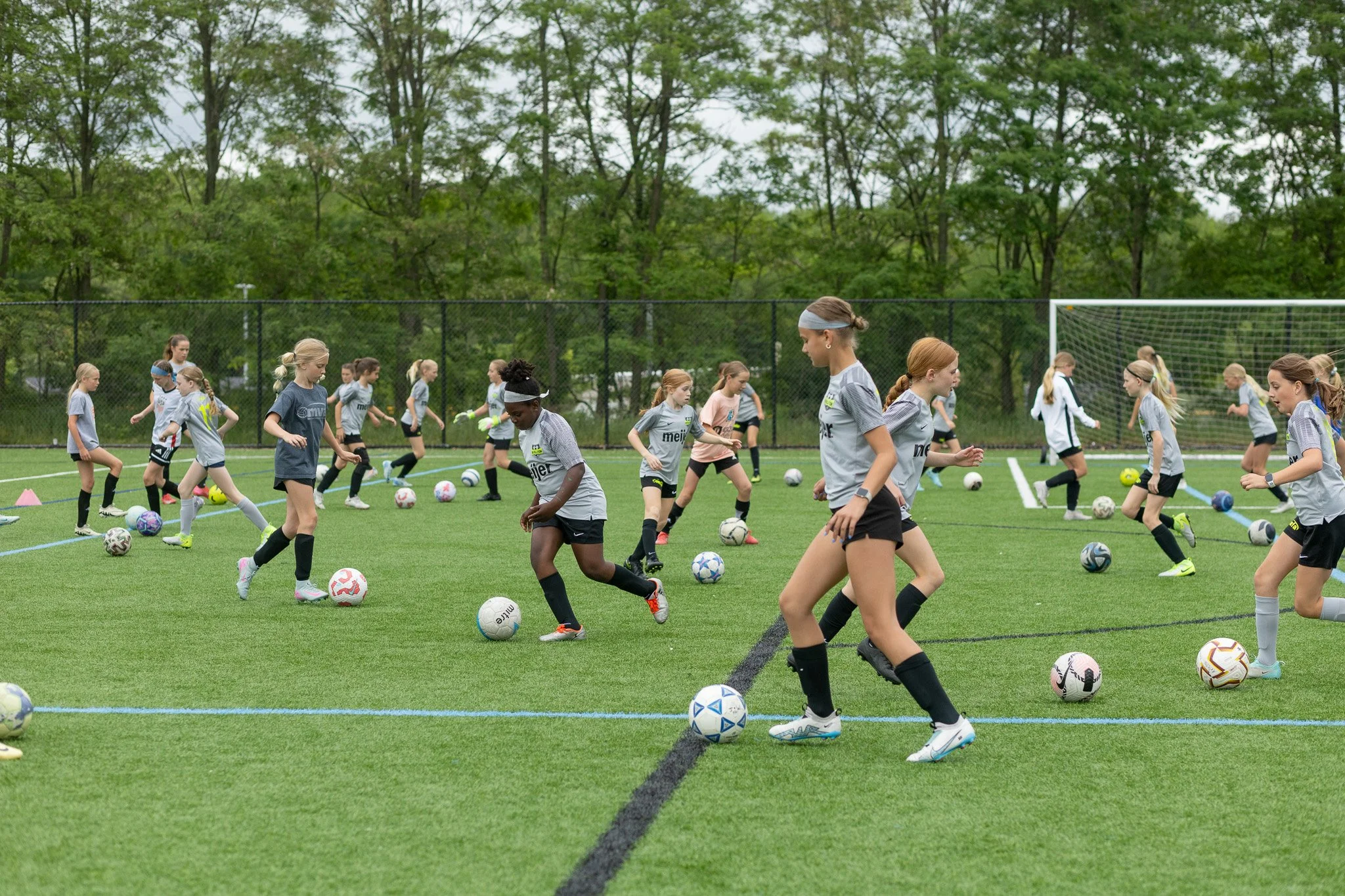 Young girls practicing soccer drills on an outdoor field.