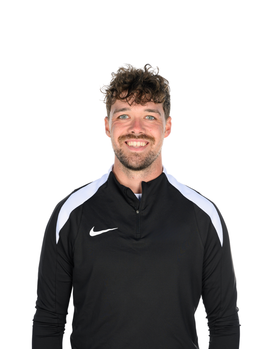 A young man with curly brown hair and blue eyes wearing a black Nike sports jacket with white accents, smiling against a white background.