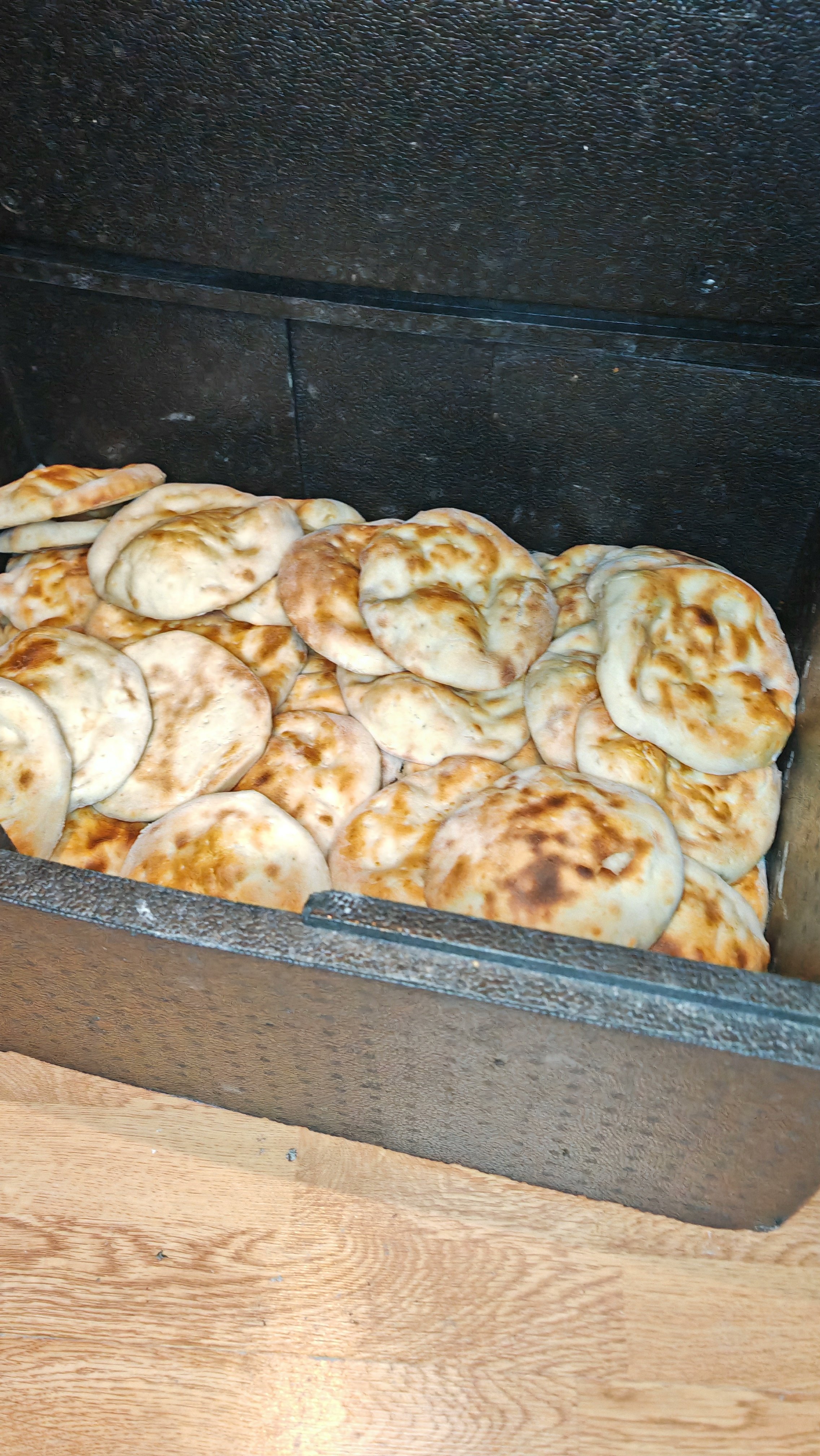 Gefüllte, gebratene Teiglinge in einer Backbox, typischerweise Fladenbrot oder ähnliches.