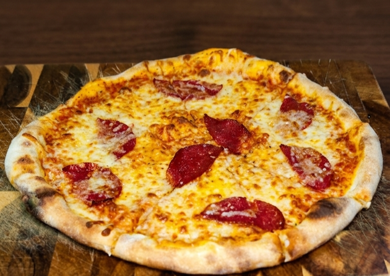 Eine Pizza mit Käse und Salami auf einer Holzplatte