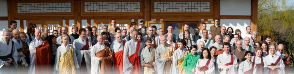 Group of people dressed in traditional Asian robes outside a building with wooden accents