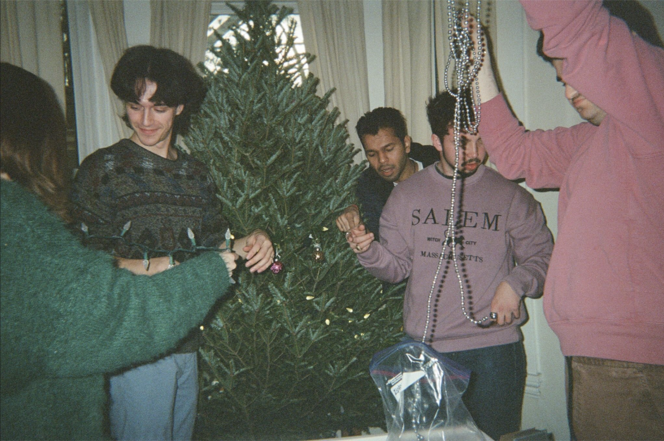 Group of young people decorating a Christmas tree with ornaments and beads