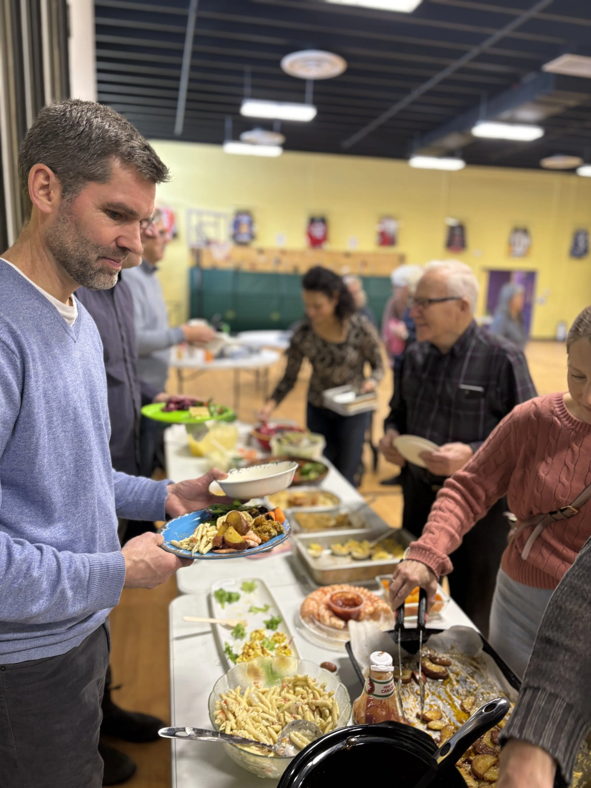 People at a buffet table serving food at a social gathering.
