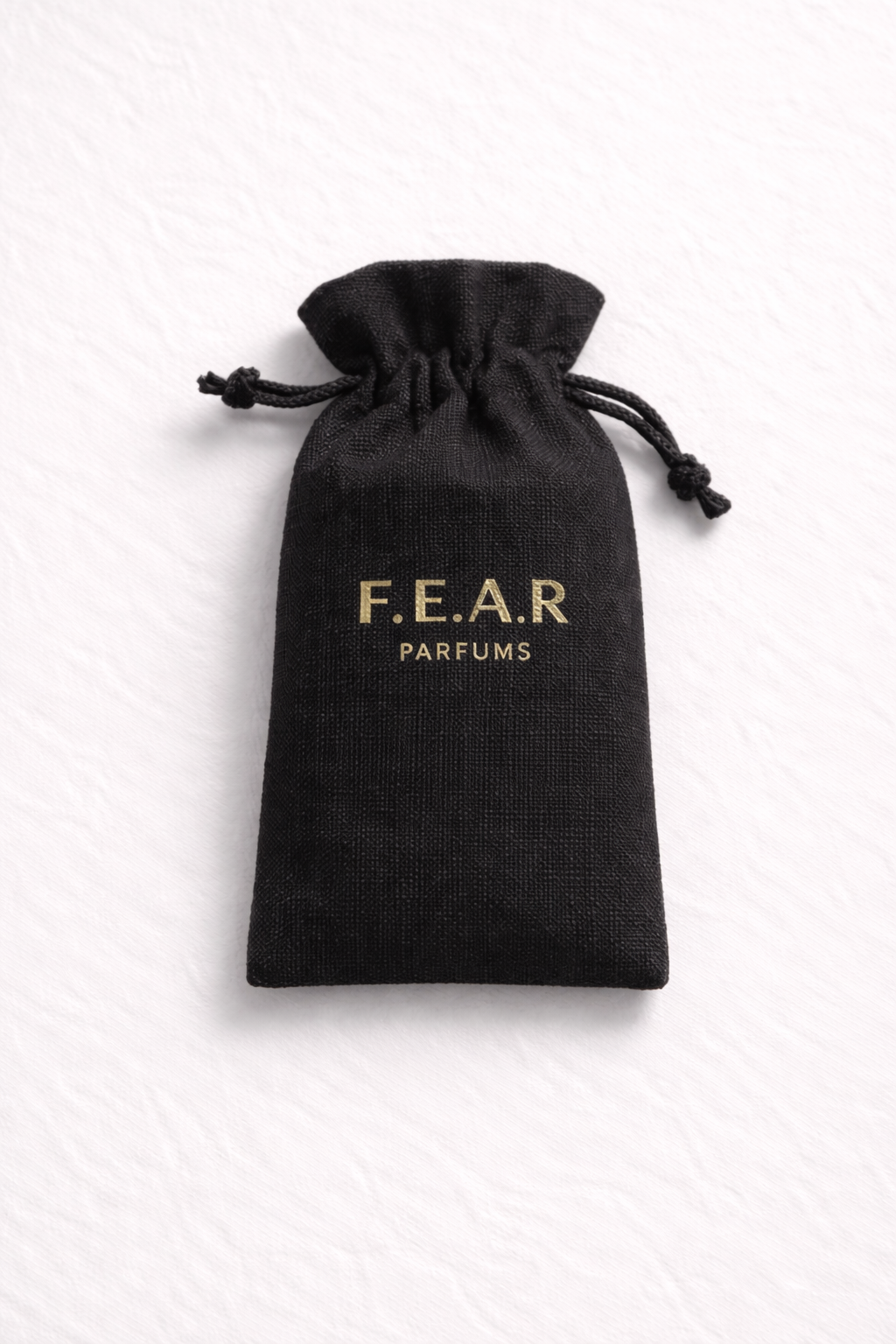 A black drawstring pouch with gold lettering that reads "F.E.A.R PARFUMS."
