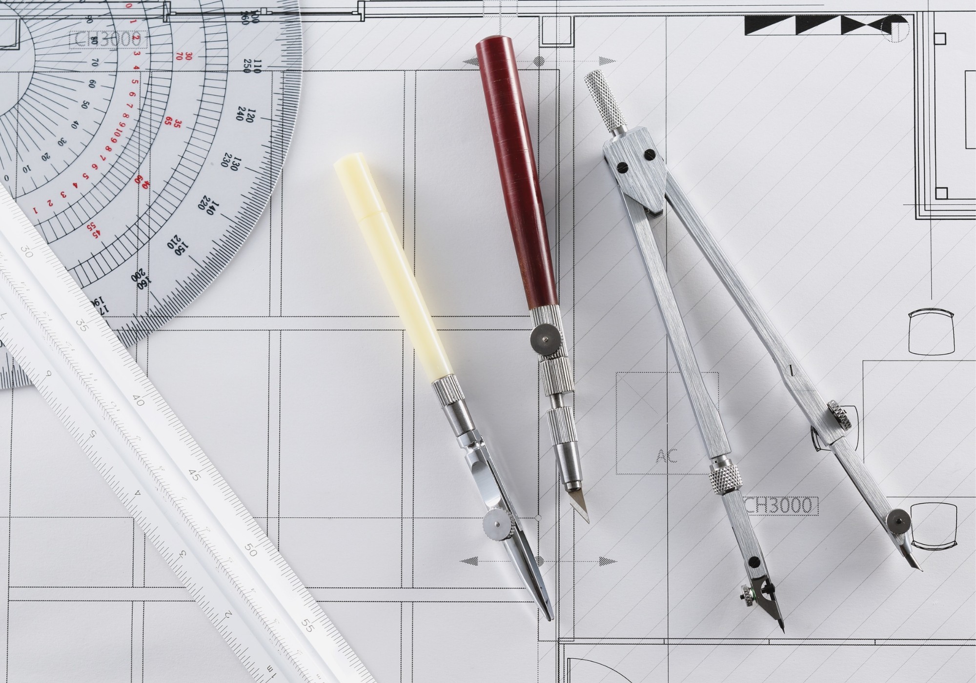 Architectural drafting tools, including a compass and protractor, placed over floor plans to represent the technical precision Monica O'Keefe brings to the home-buying process.