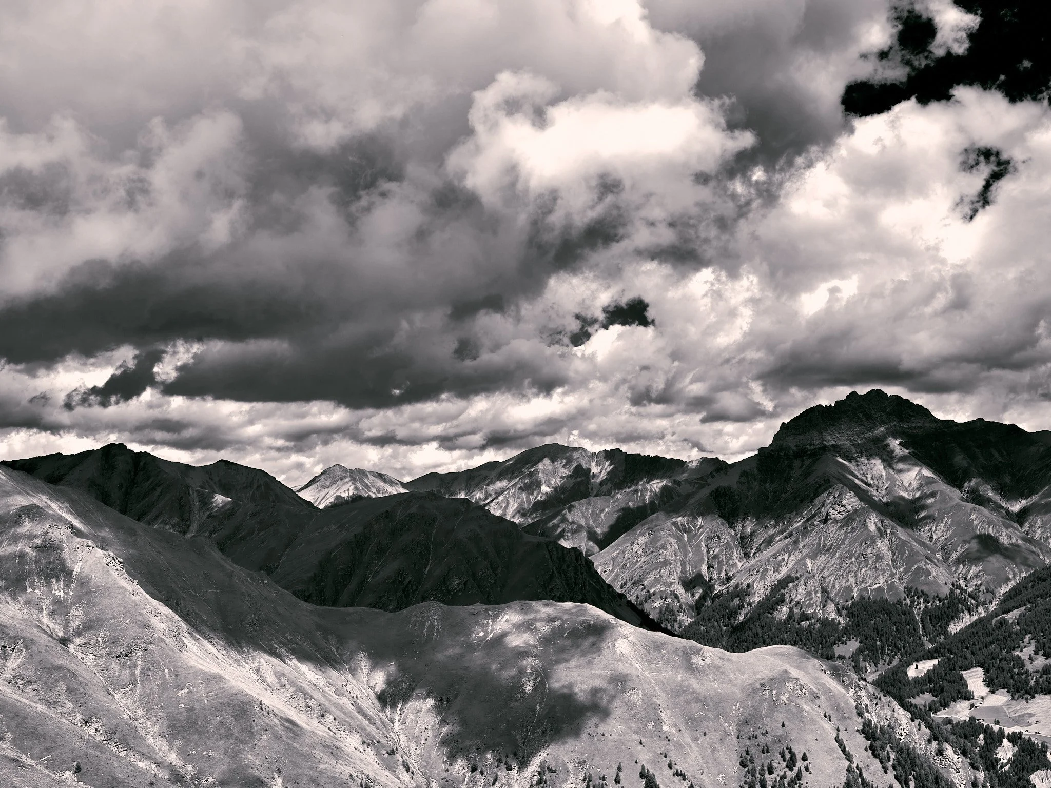 Black and white landscape of mountains under a cloudy sky.