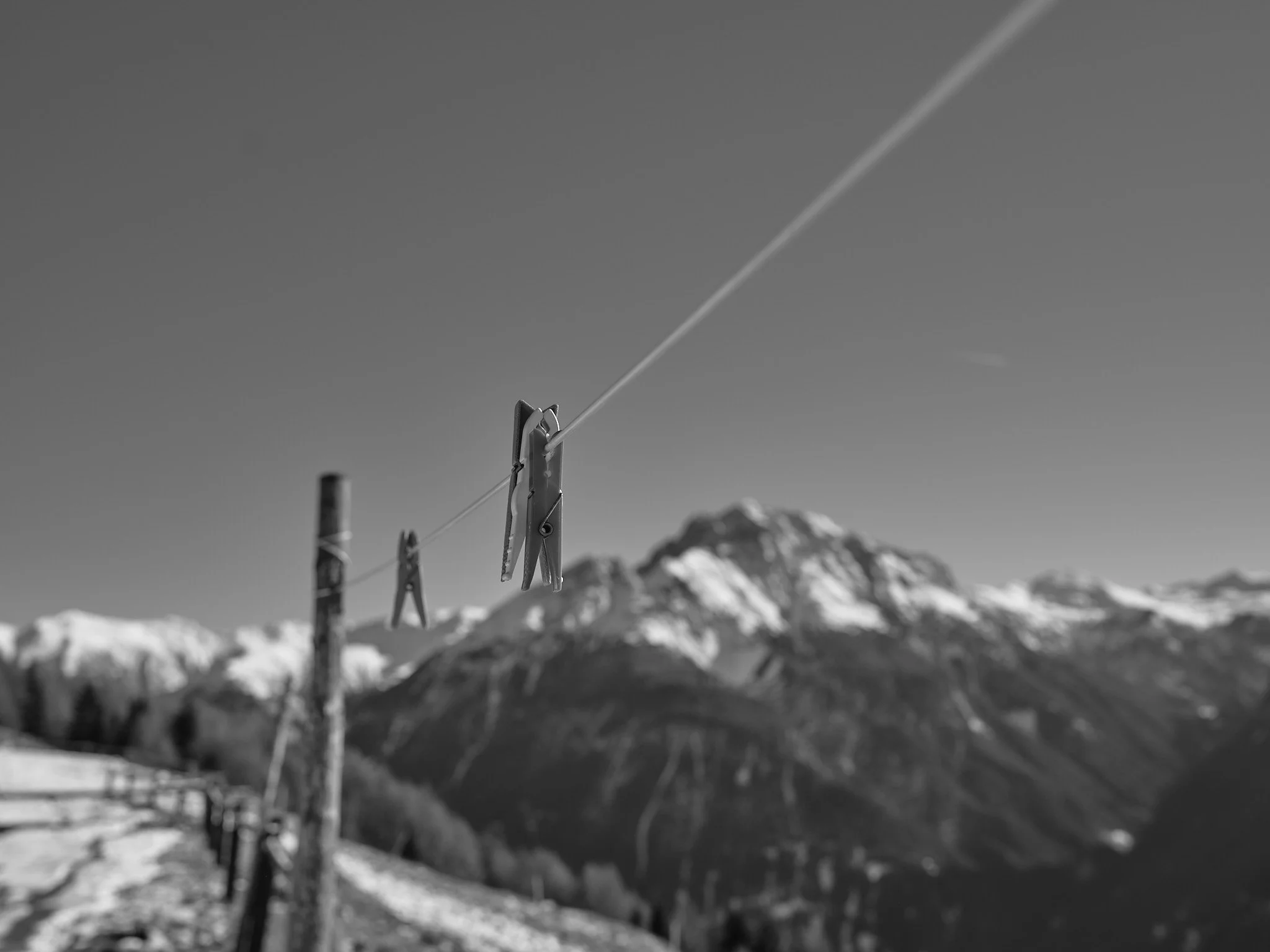 Clothes pins hanging on a wire with mountain peaks in the background.