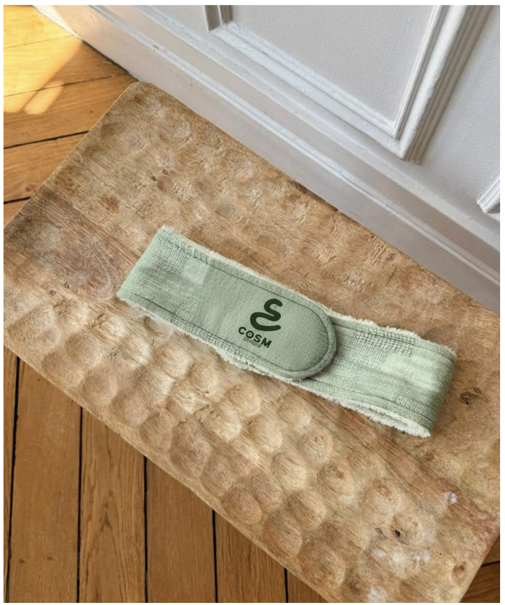 Une bande de sport verte avec un logo de serpent et le texte 'COSM' posée sur un tabouret en bois.