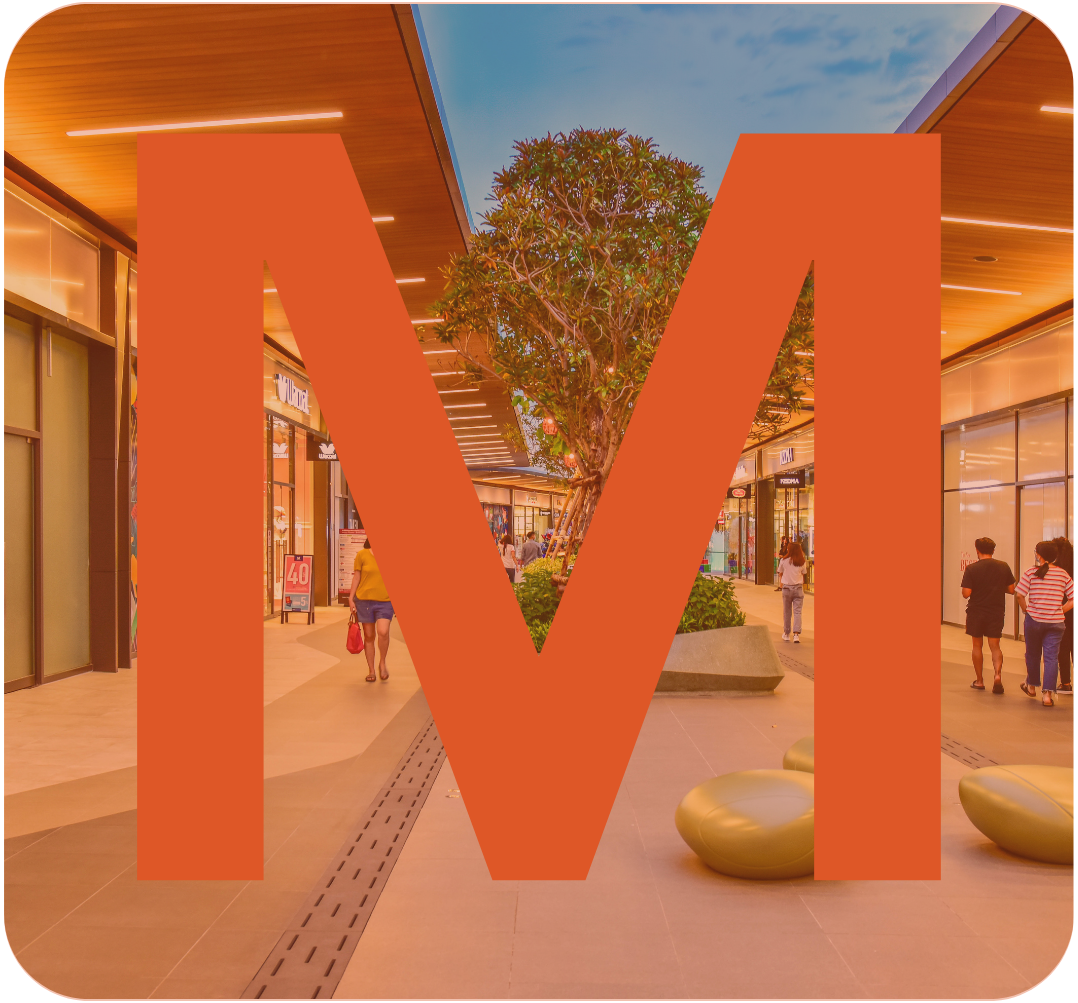 A shopping mall walkway with stores on both sides, large orange letter 'W' overlay, and a central tree with green leaves under a partly cloudy sky.