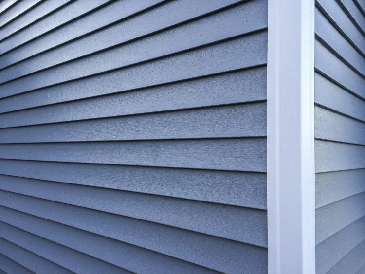 Close-up of blue horizontal vinyl siding on a building with white trim.