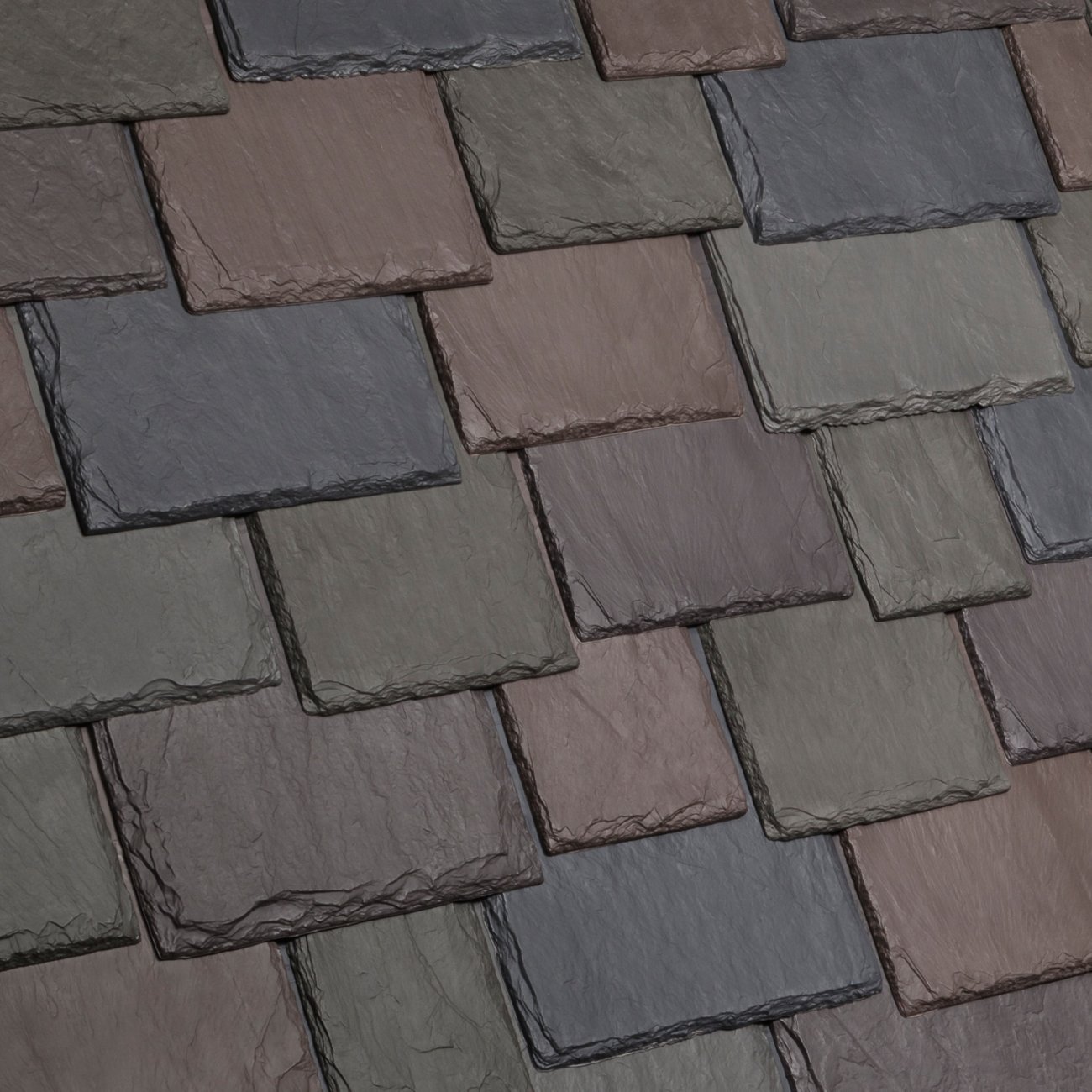 Close-up of a multicolored slate tile roof with a textured surface, arranged in a staggered pattern.