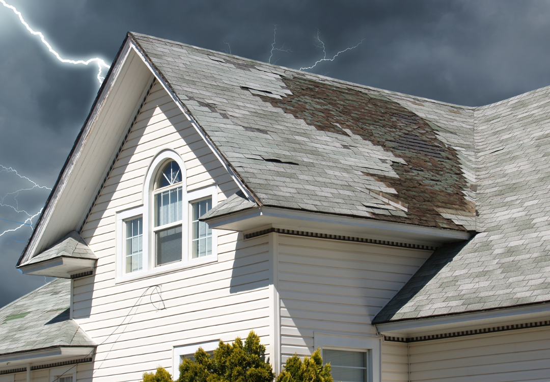 House with damaged roof during a thunderstorm with lightning in the sky.