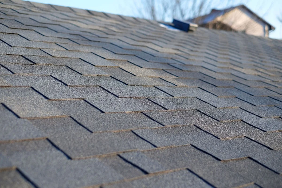Close-up of a gray shingle roof with overlapping asphalt shingles.