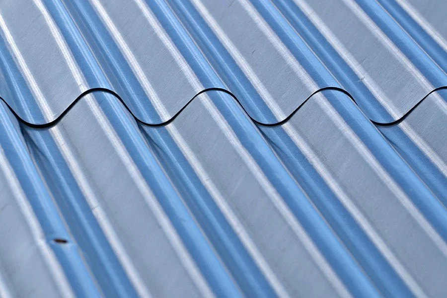 Close-up of a metallic corrugated roof with a black wire running across it.