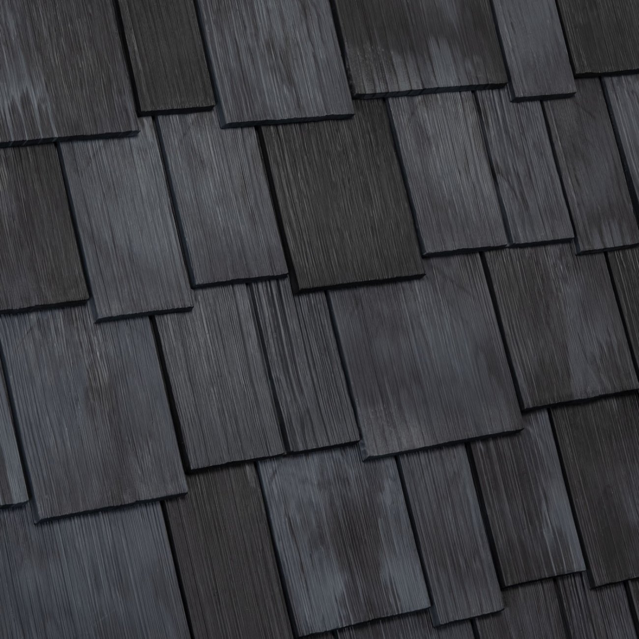 Close-up view of dark gray asphalt shingles on a roof.